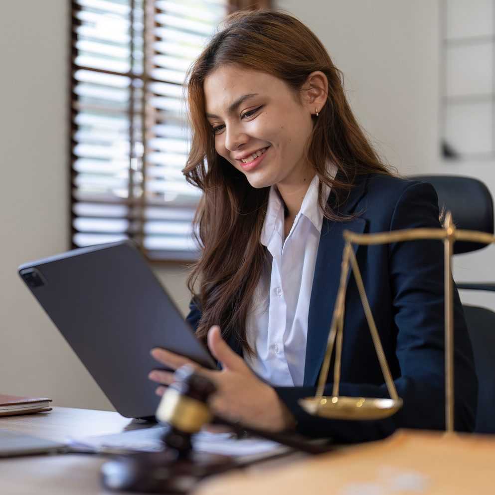 female-lawyer-smiling-while-looking-at-a-tablet