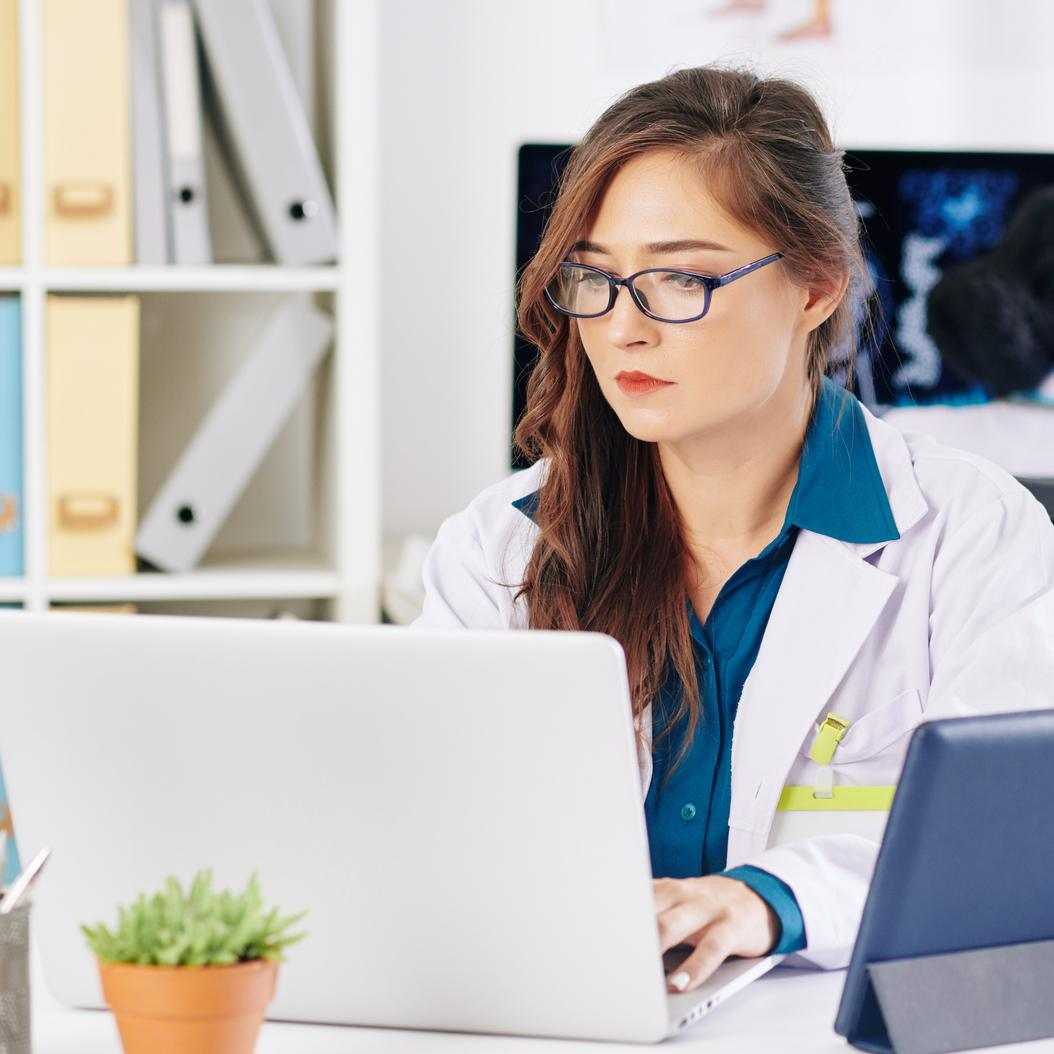  Woman in a Lab Coat and Glasses Working on a Laptop