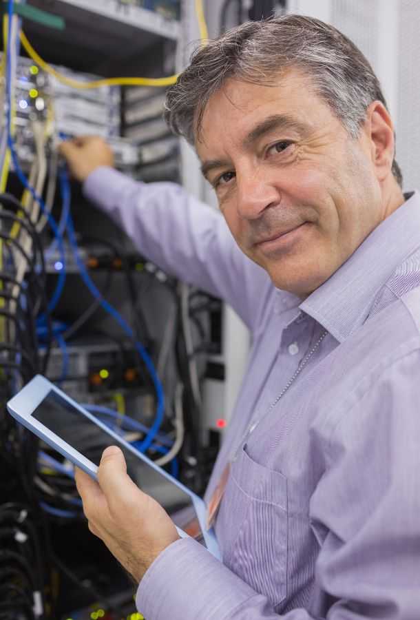 Man Smiling While Doing Server Maintenance With Tablet