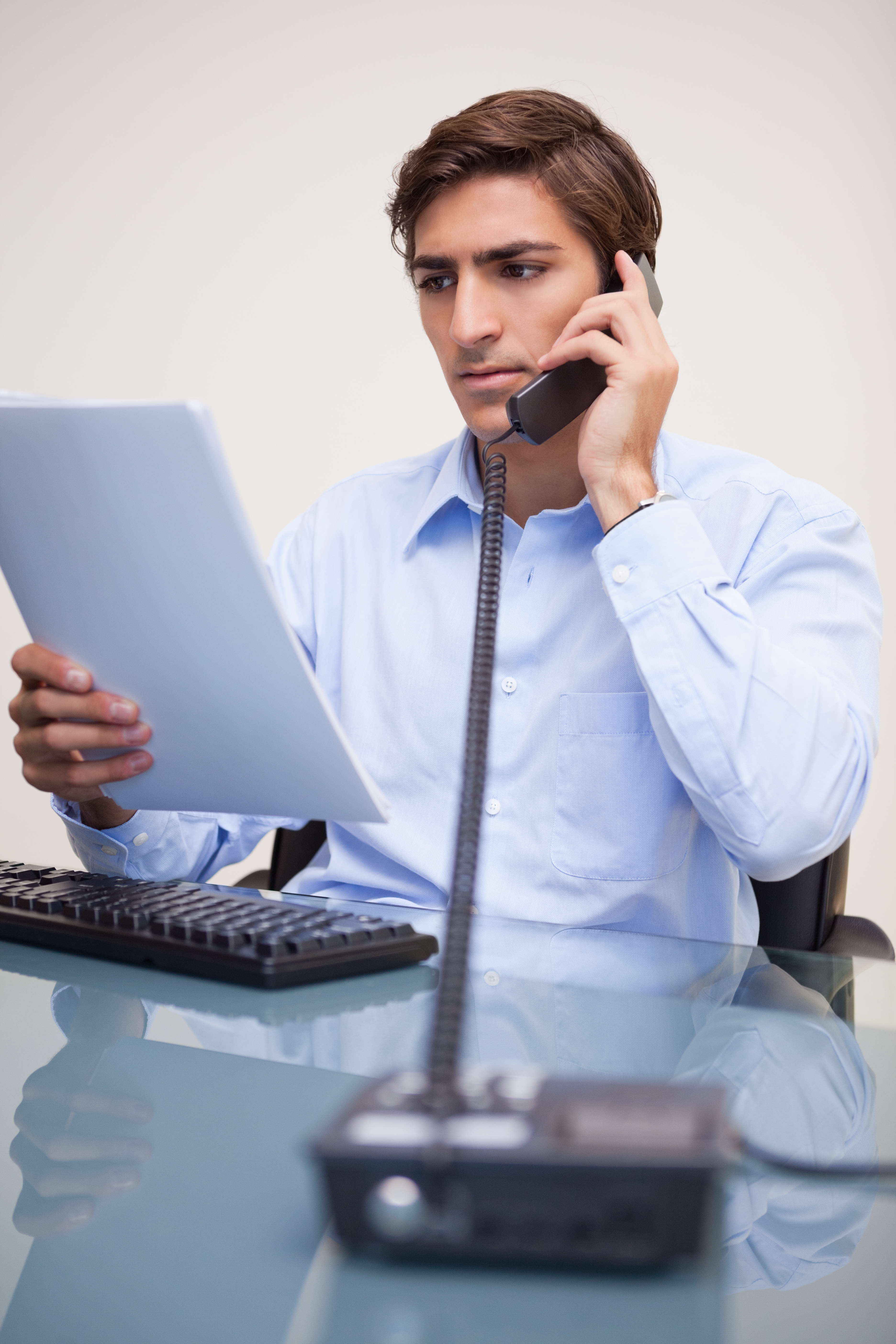 Young business man looking at document while on call at office Cloud Computing
