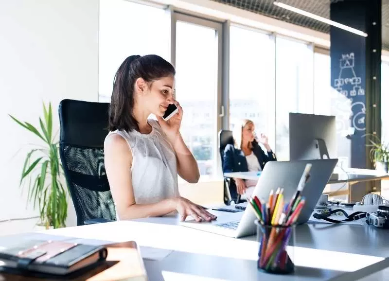 Woman Talking on Phone While Using Laptop